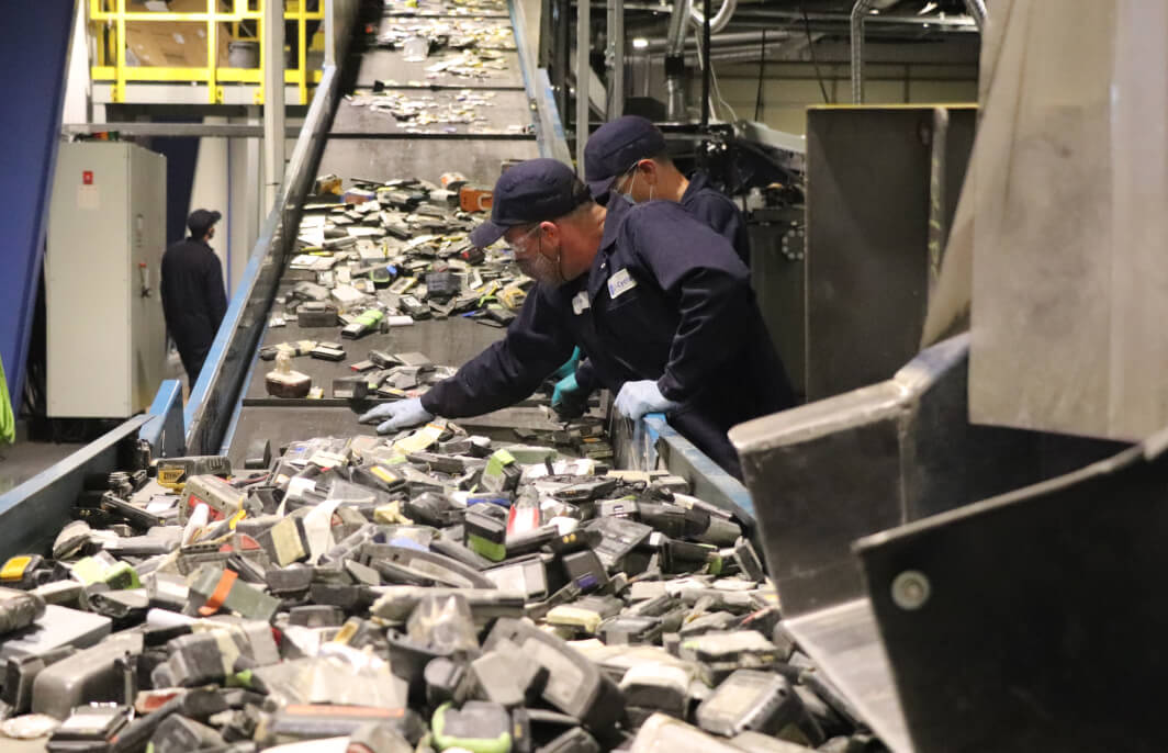 Li-Cycle employees sorting batteries on conveyor belt to be shredded