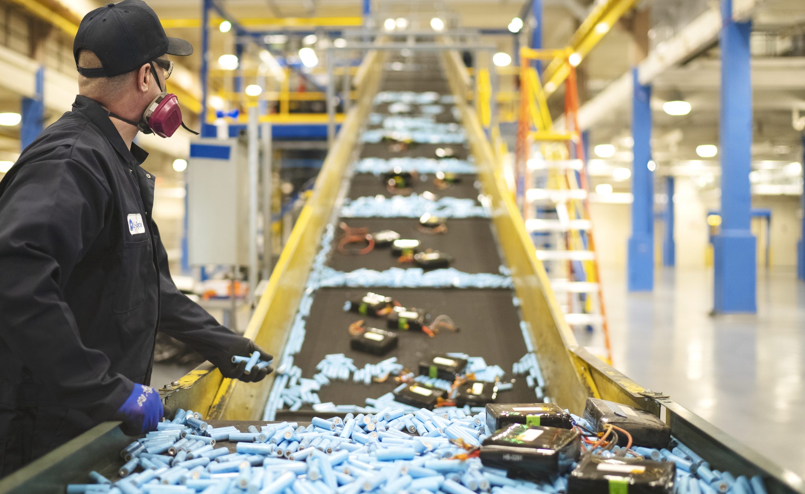 Li-Cycle employee adding lithium-ion batteries to conveyor belt to be shredded