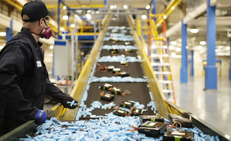 Li-Cycle Spoke operator loads batteries onto conveyor belt for shredding