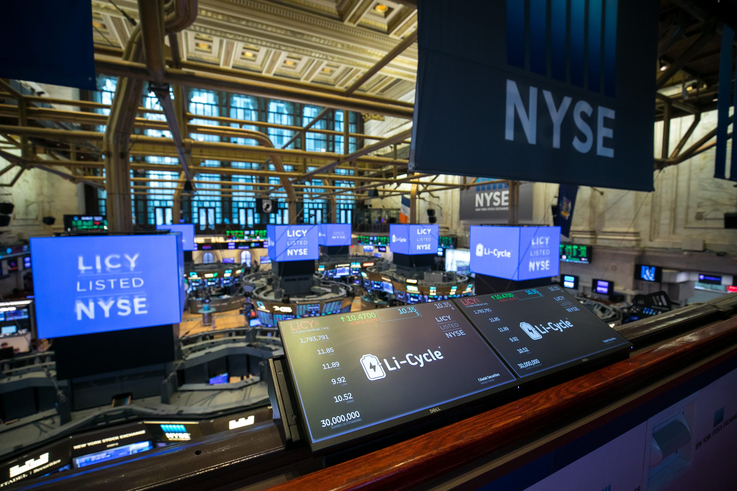 Photo of interior of New York Stock Exchange. Screens have the Li-Cycle logo and read 