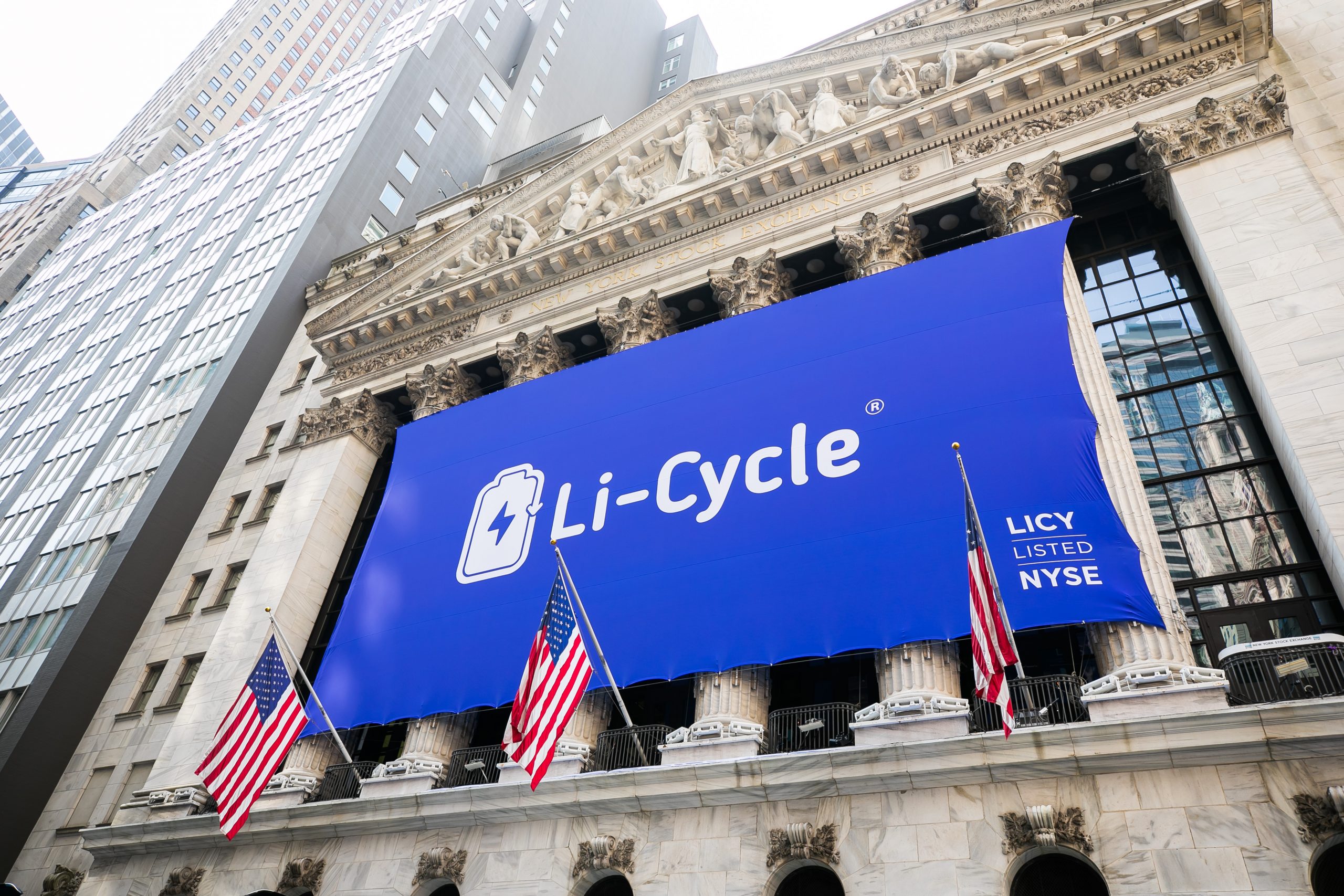 White Li-Cycle logo on large blue banner hung at the exterior of the New York Stock Exchange