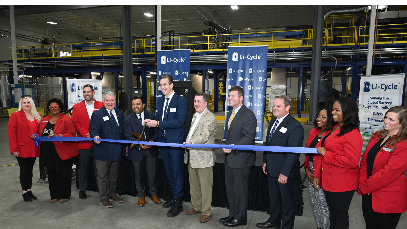 Group photo of a ribbon cutting ceremony in an industrial building.