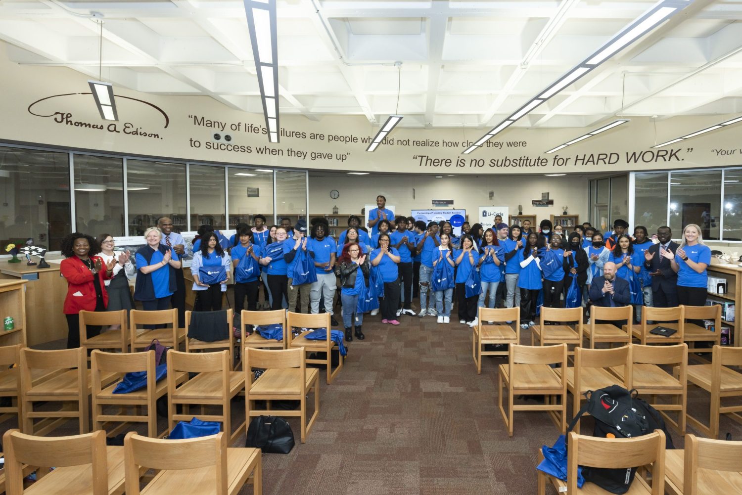 Group photo showing students wearing blue Li-Cycle t-shirts and holding blue Li-Cycle tote bags containing donated laptops.